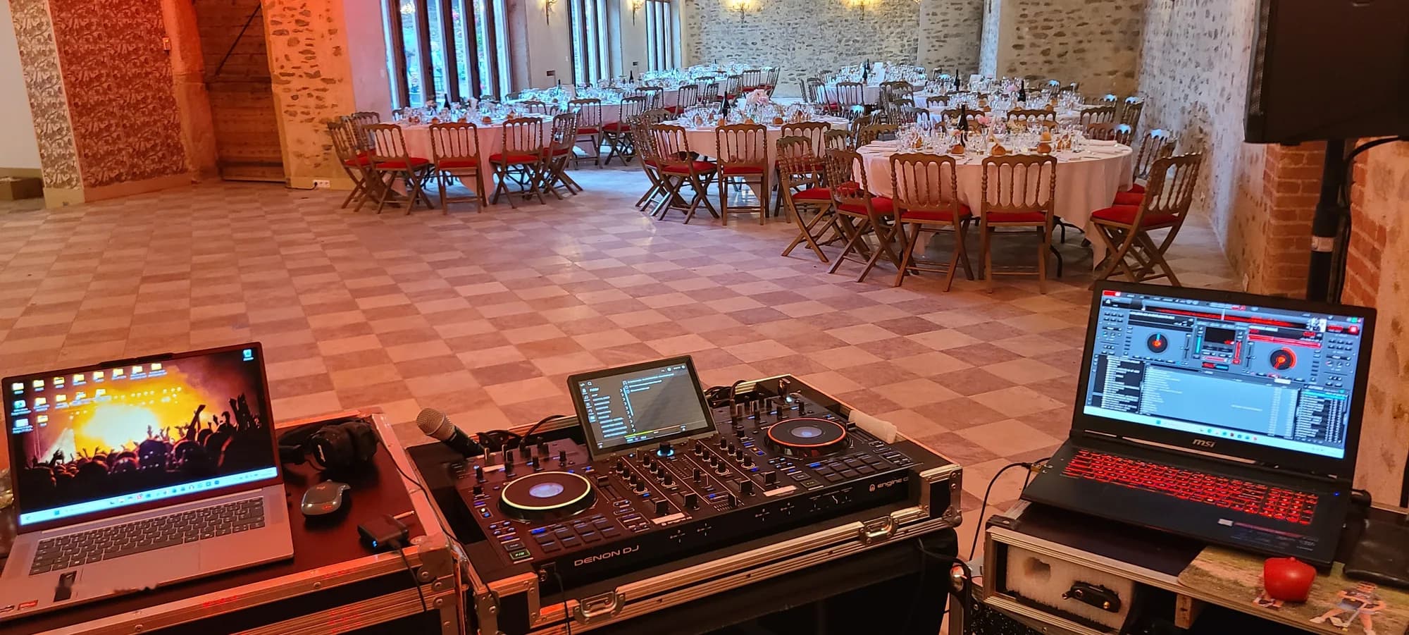 Régie DJ avec contrôleur Denon Prime 4 et deux ordinateurs portables, face à une salle de mariage dressée