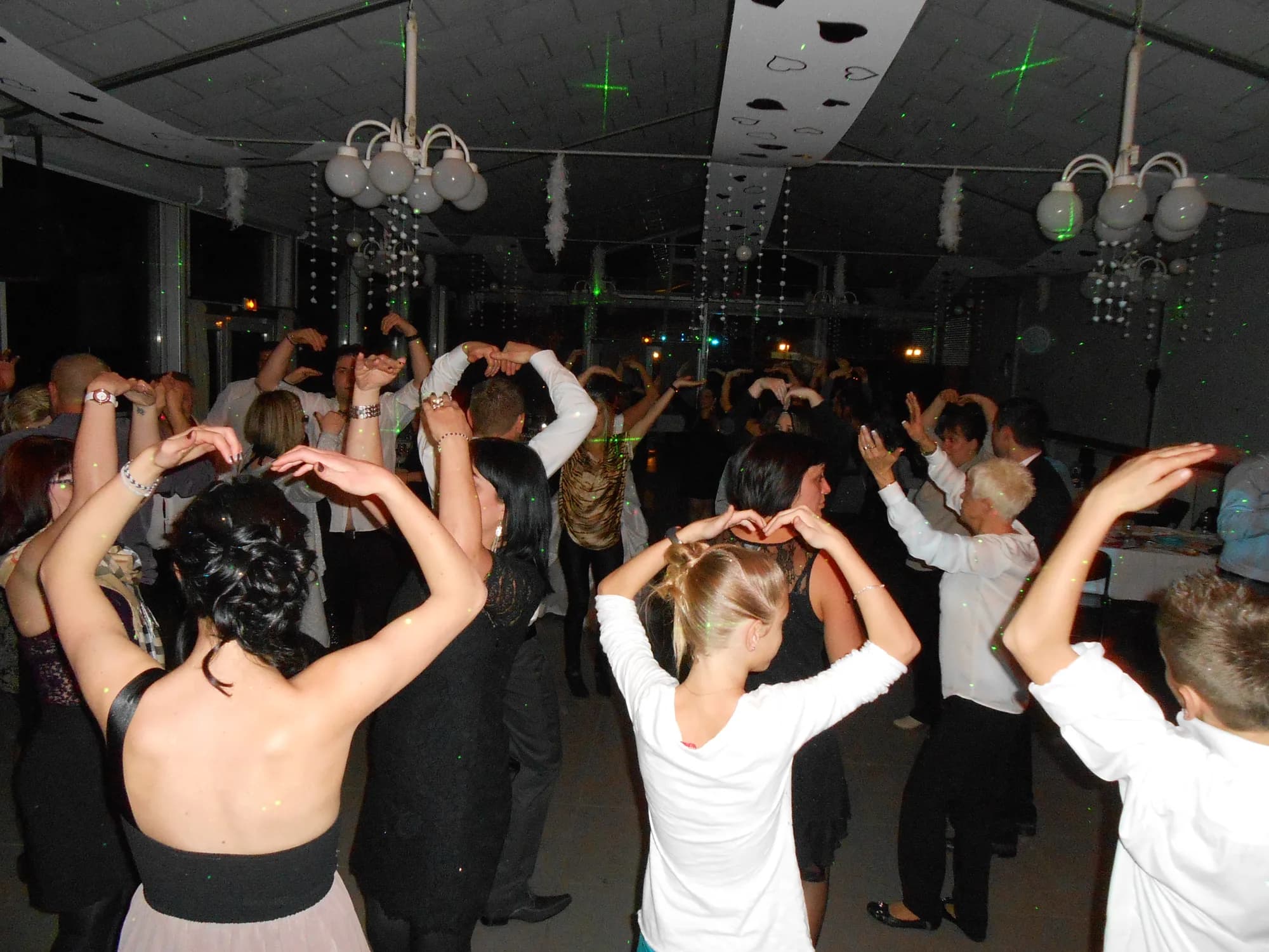 Invités serrés sur la piste de danse, bras levés au-dessus de la tête, sous des faisceaux laser verts